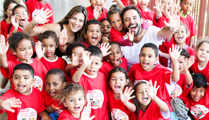 Group of children and adults smiling and waving at the camera while wearing "Bright Smiles, Bright Futures" shirts.